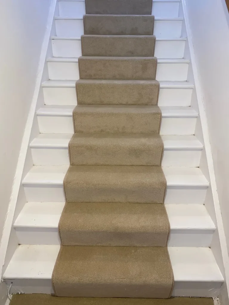 Beige stair runner on a white painted staircase